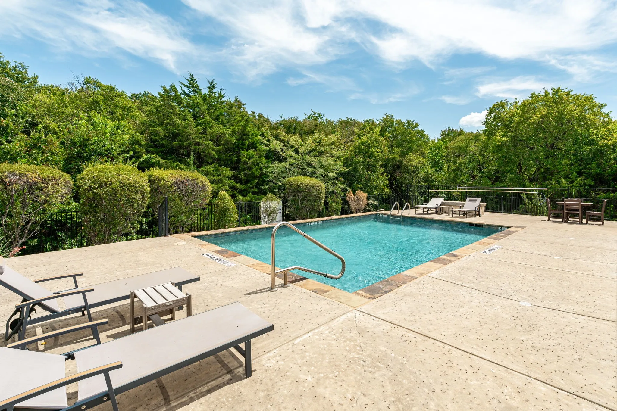 Outdoor community swimming pool with integrated steps, surrounded by a concrete deck