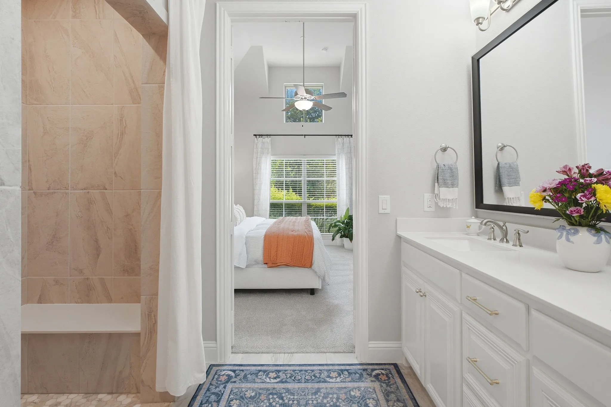 Vanity with a white countertop and undermount sink, framed mirror, and tiled shower with an integrated bench