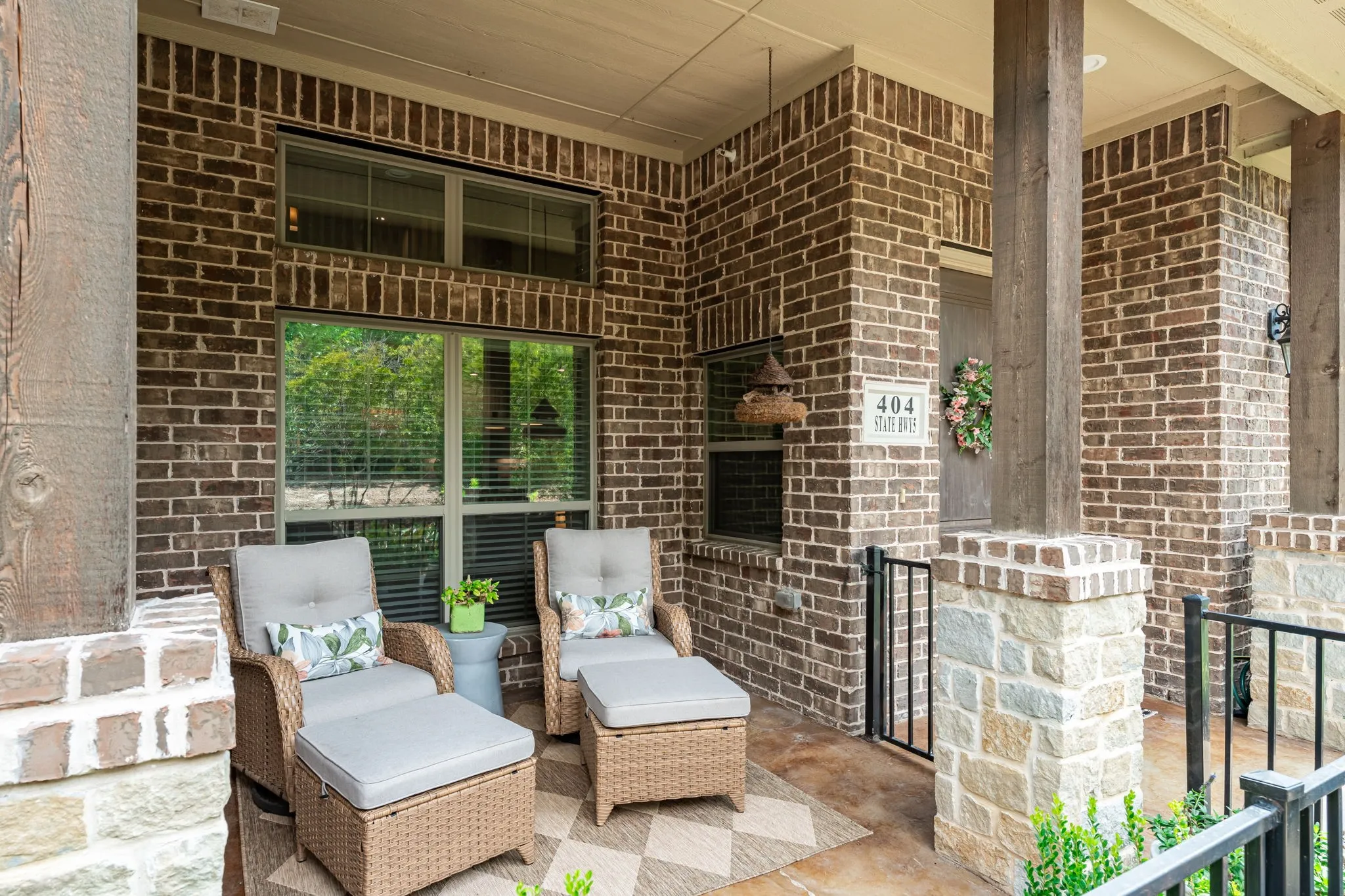 Brick exterior with stone accents, covered porch with wood columns, and concrete flooring
