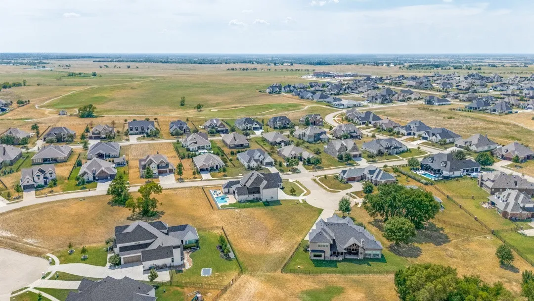 Expansive residential development with numerous single-family homes, private swimming pools, and surrounding open land
