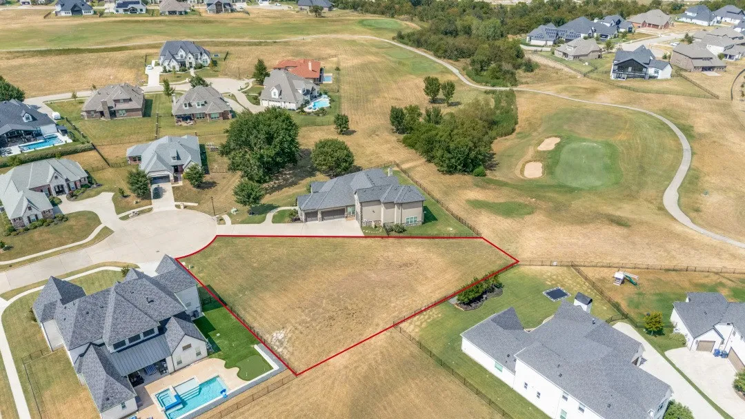 Vacant land with established residential properties and golf course greens in the background
