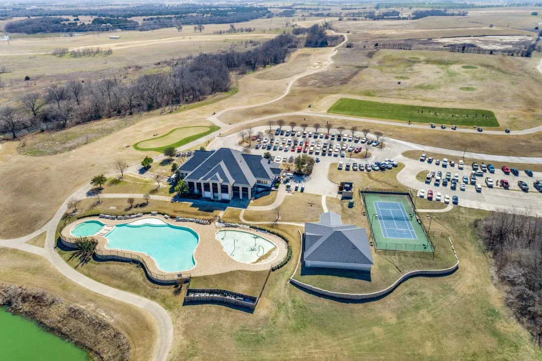 Community clubhouse, two swimming pools, tennis court, and expansive parking areas, surrounded by green spaces