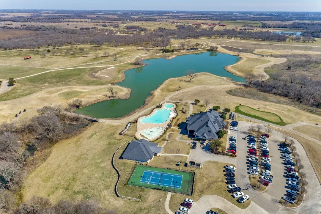 Expansive property featuring a large lake, two swimming pools, a tennis court, and a clubhouse