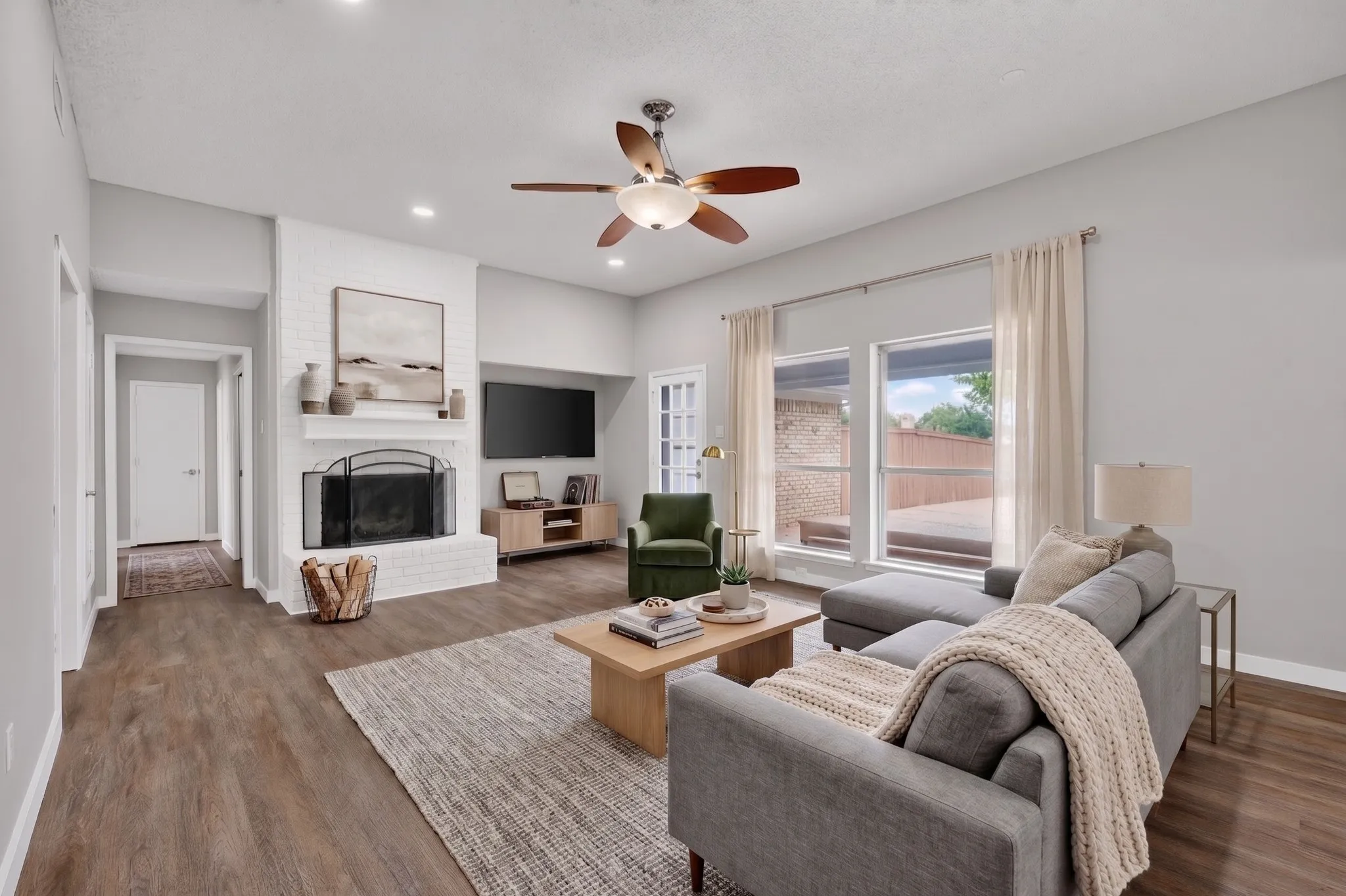 Living area featuring wood-finish flooring, a white brick fireplace, recessed lighting, and a ceiling fan