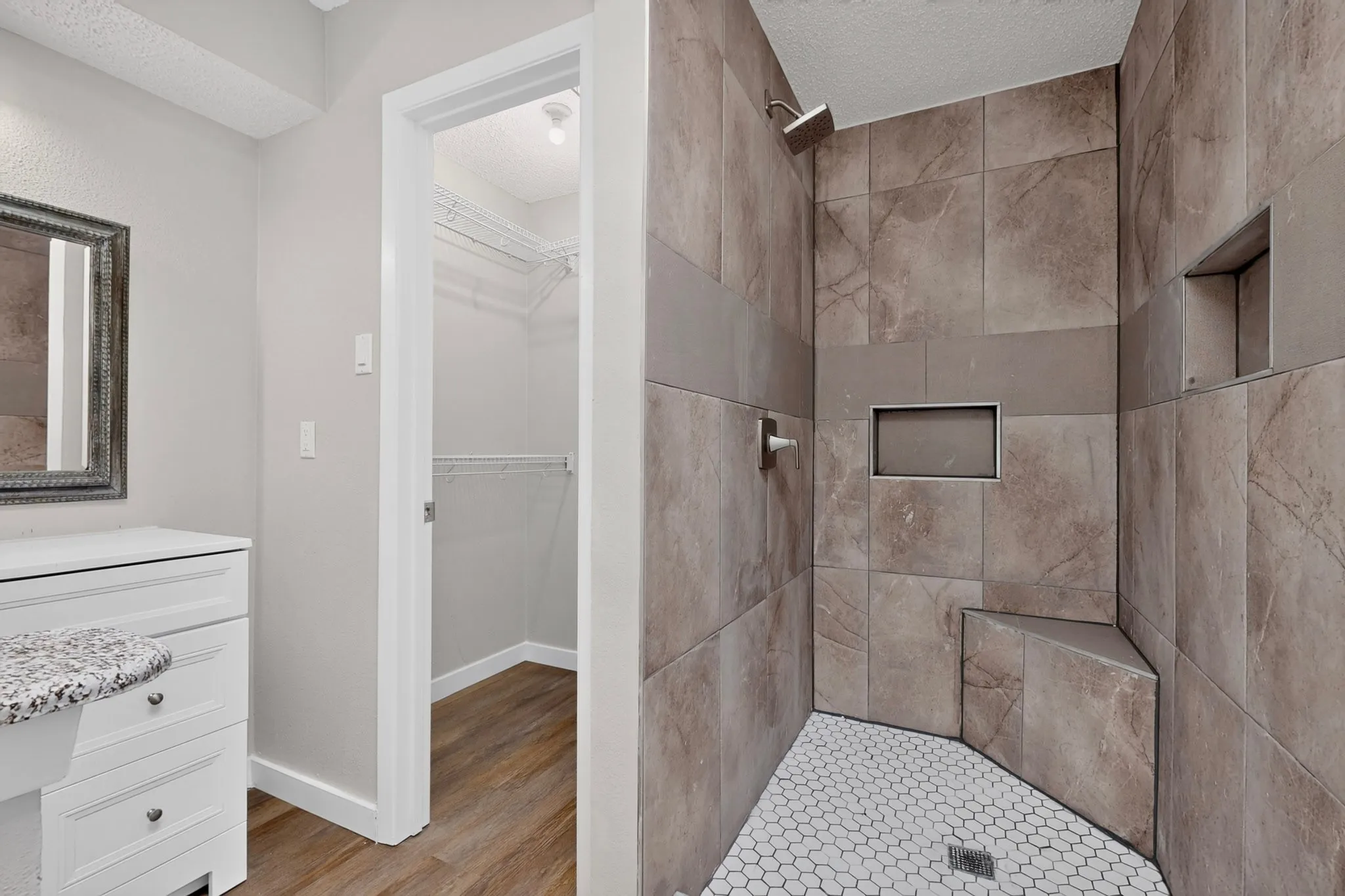 Shower with tiled walls, integrated niche shelving, and a built-in bench