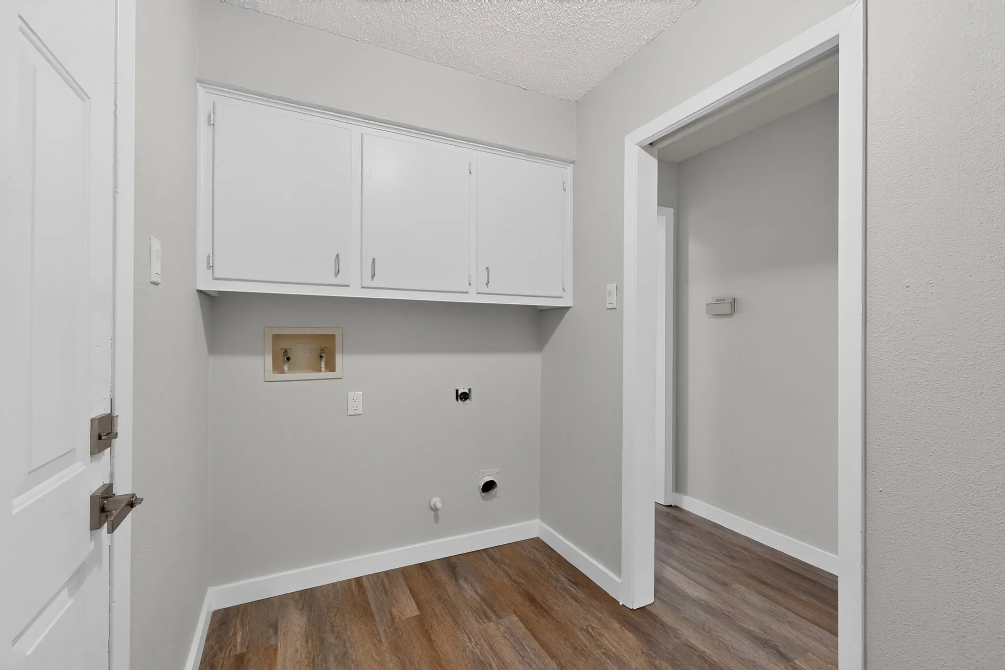 Utility area featuring wood-finish flooring, white cabinetry, and light gray walls