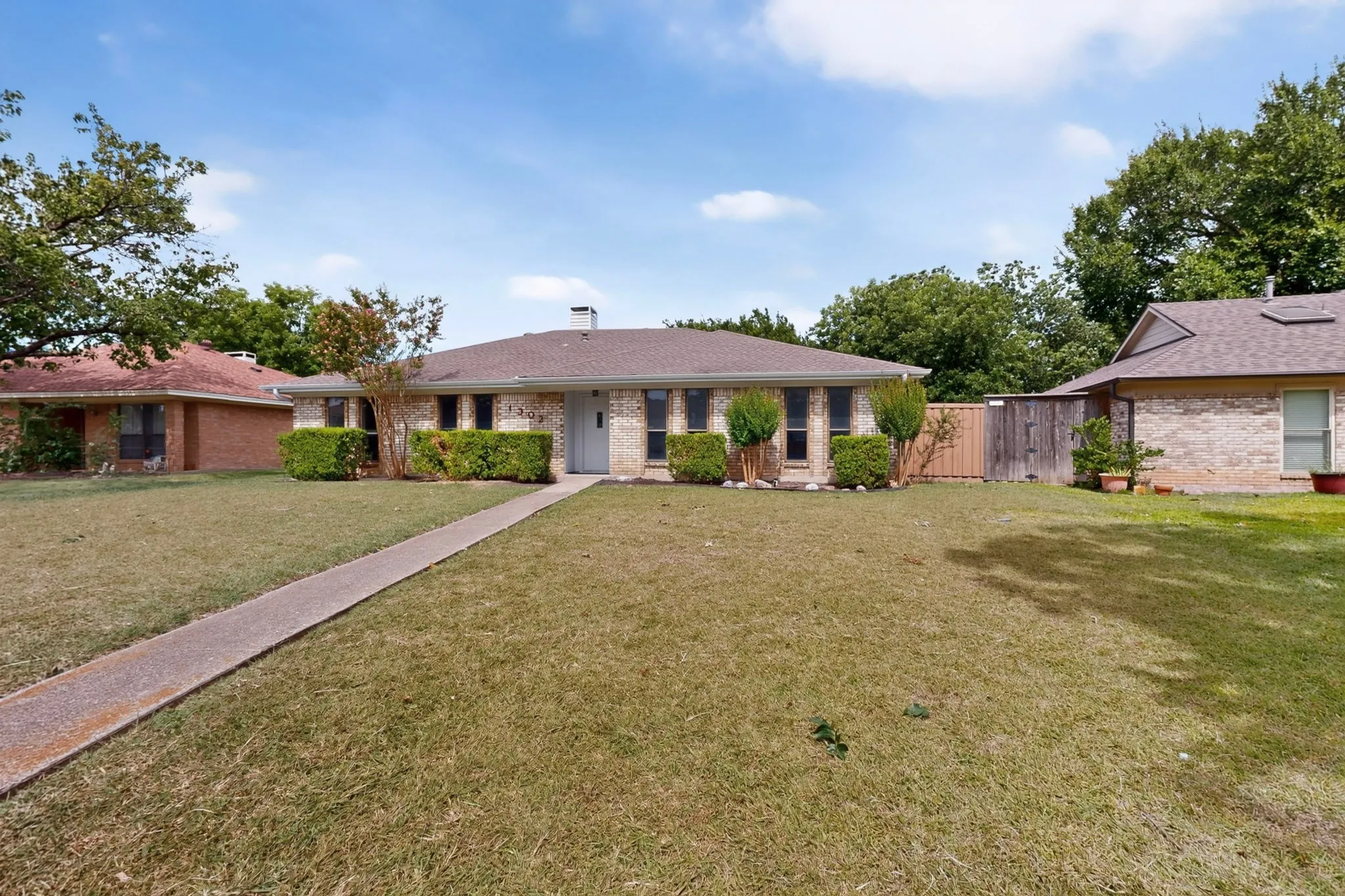Brick exterior with a shingle roof and a concrete walkway