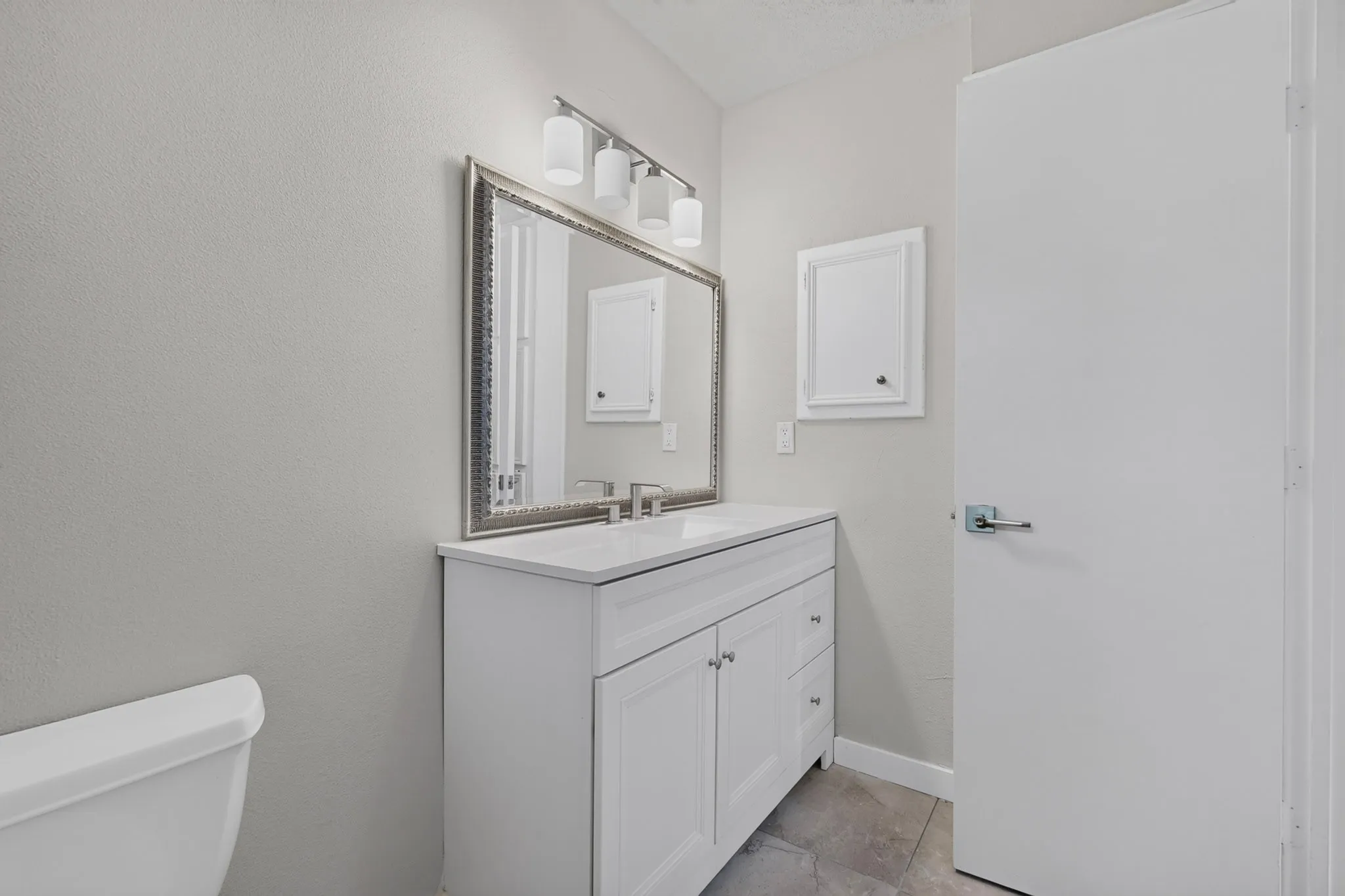 White vanity with shaker-style cabinetry, a white countertop, and a rectangular undermount sink