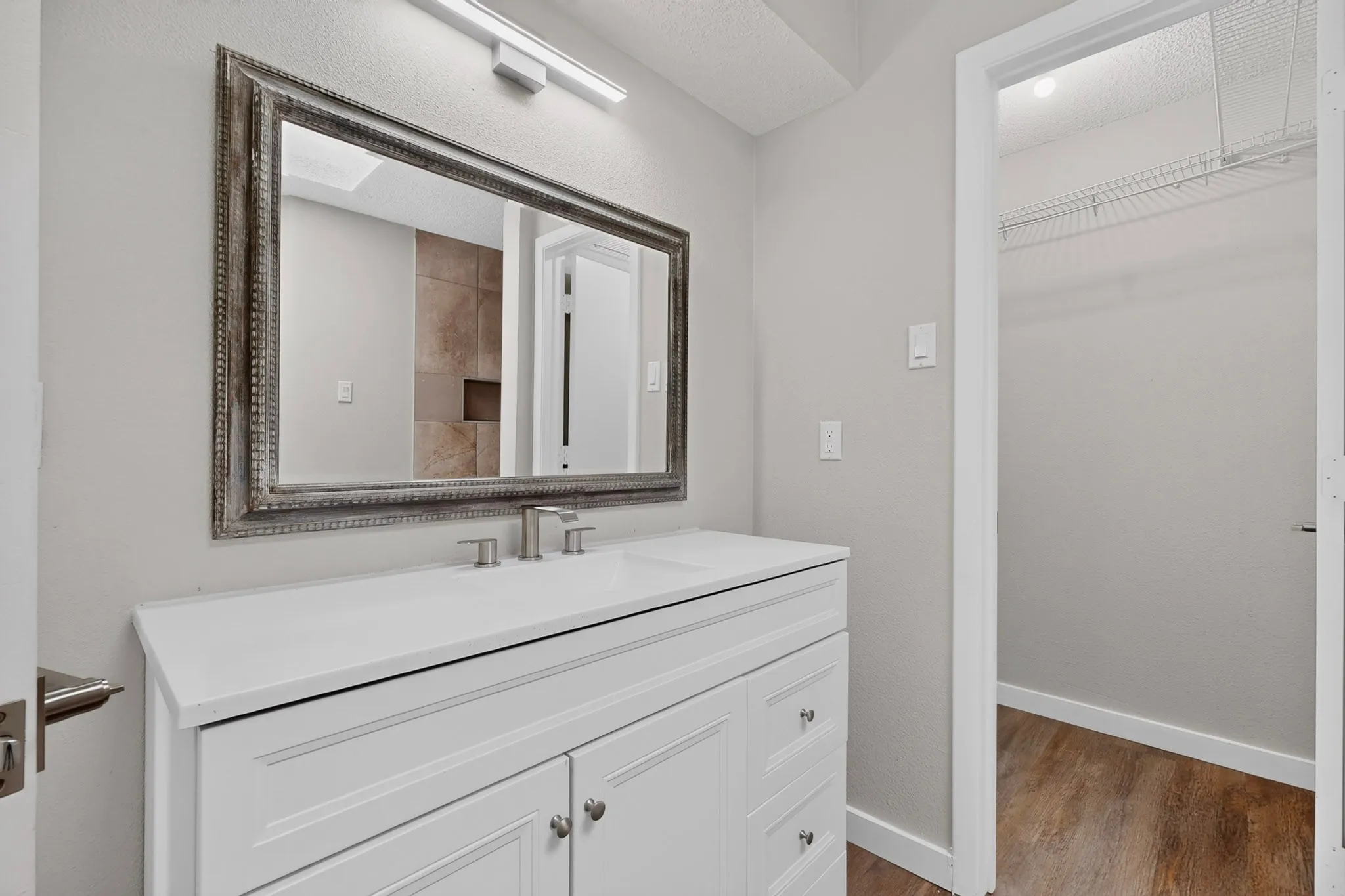 White vanity with a single basin sink and brushed nickel faucet