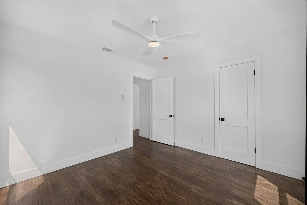 Dark wood-finish flooring, white walls, and a contemporary ceiling fan with integrated lighting