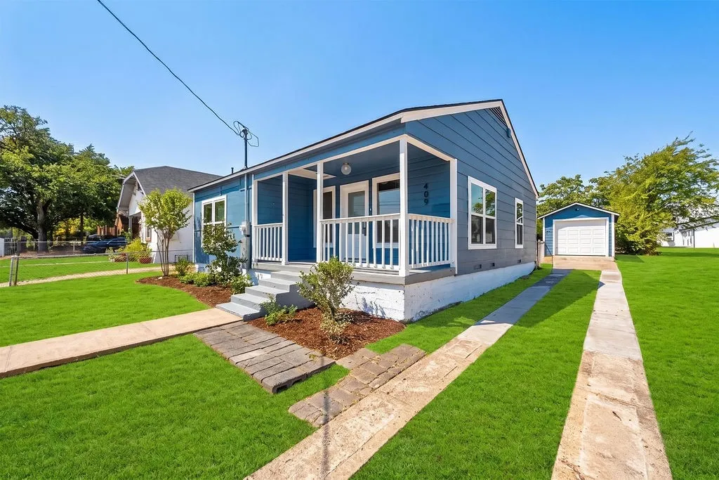 Charming contemporary residence featuring a welcoming front porch with white railings and columns, dark blue exterior siding, and multiple windows offering natural light