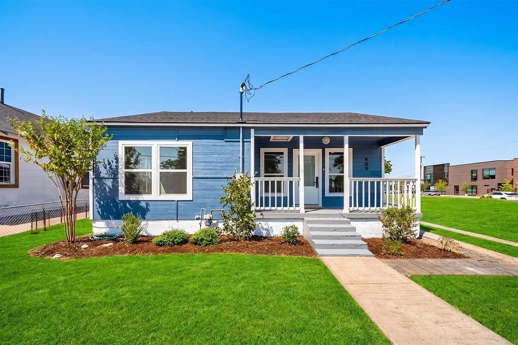 Blue horizontal siding exterior with a covered porch, white railing, and grey concrete steps