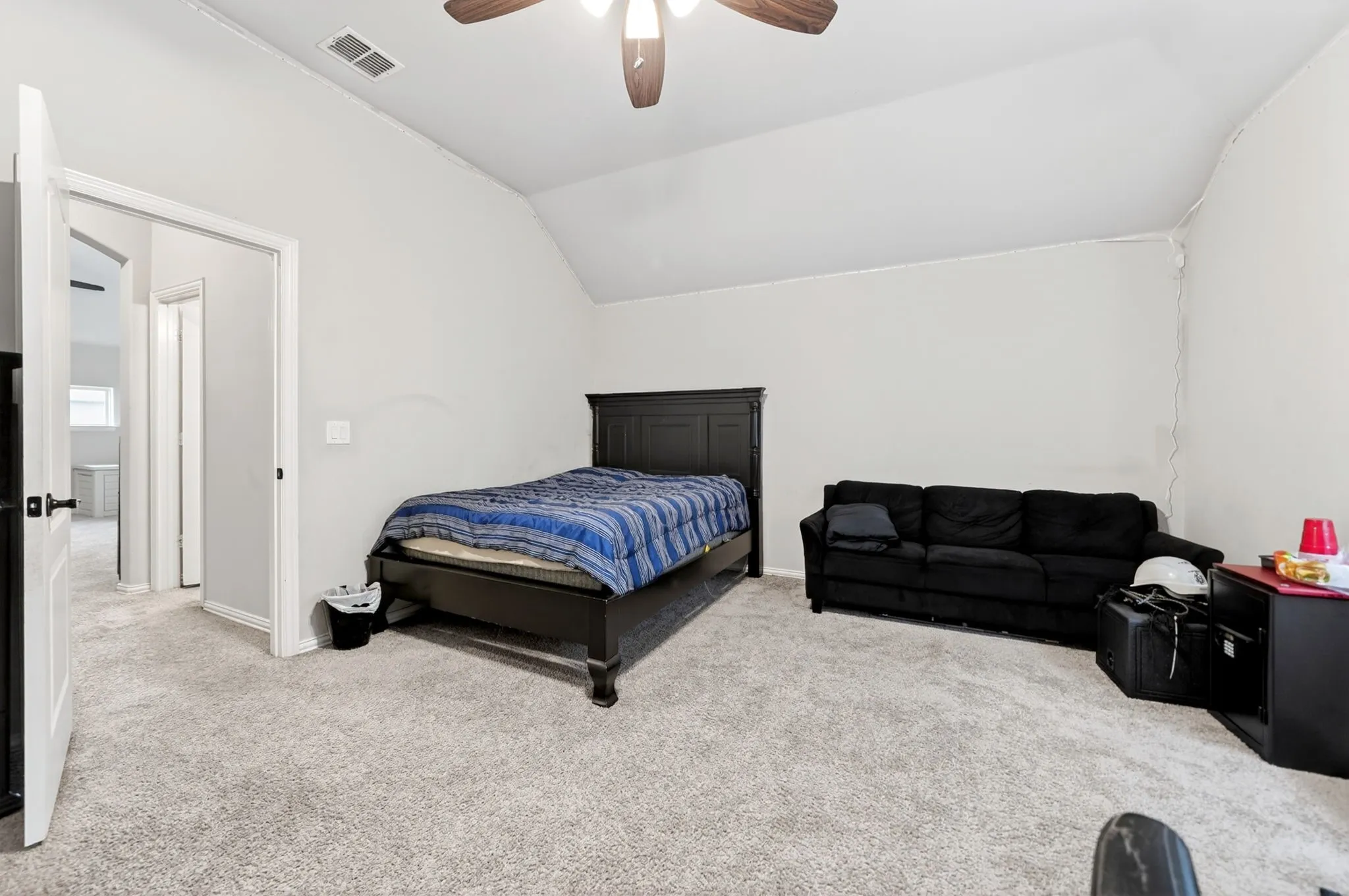 Vaulted ceiling with a ceiling fan, light-colored carpeting, and white interior doors with black hardware