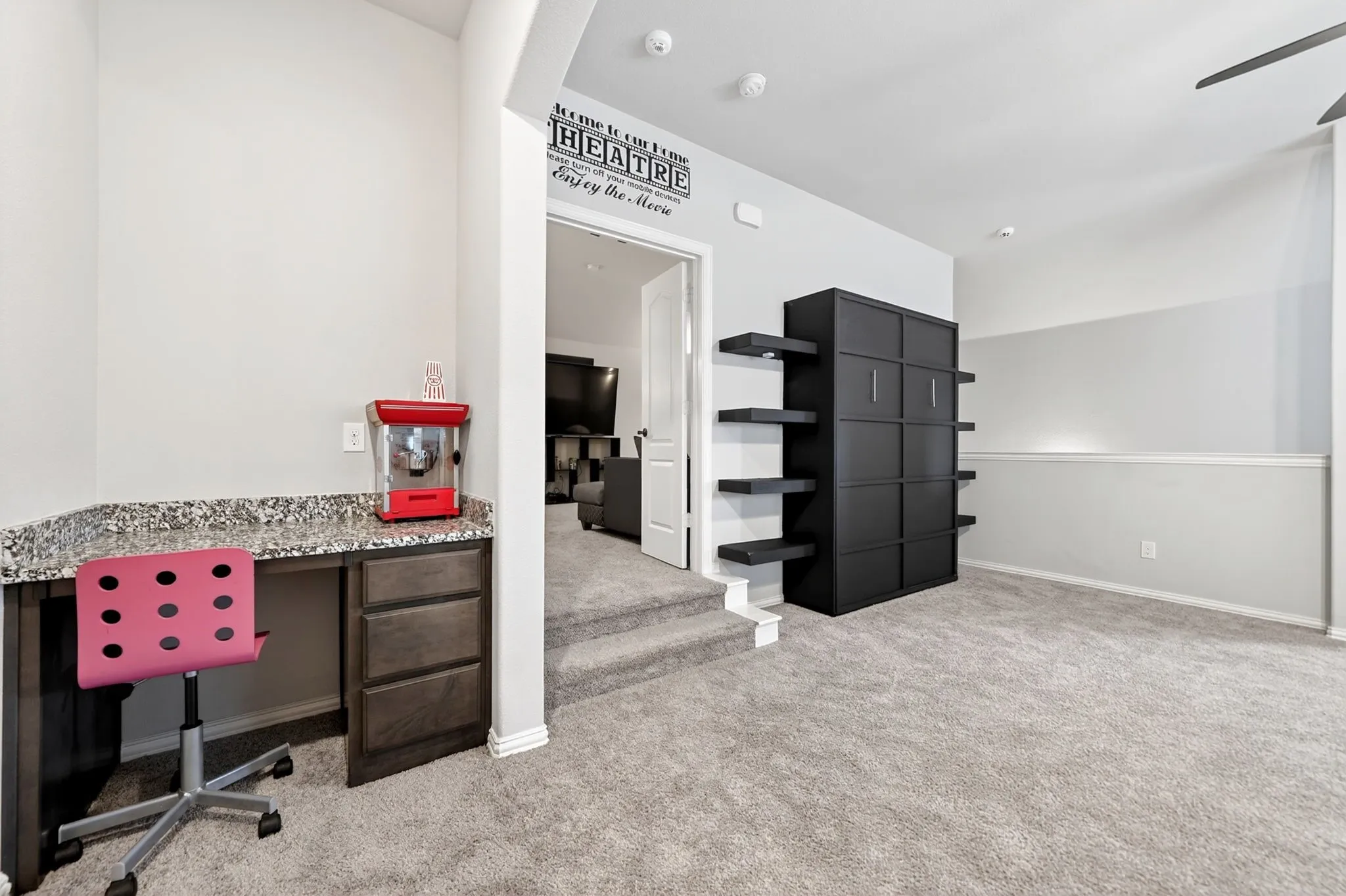 Built-in desk with a stone-finish countertop, dark wood-finish cabinetry, and carpet flooring