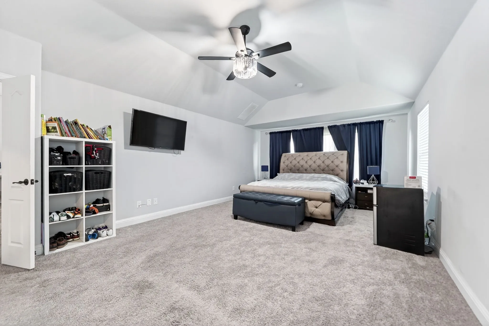 Vaulted ceiling with a ceiling fan, light gray wall paint, gray carpet flooring, and a window with blinds
