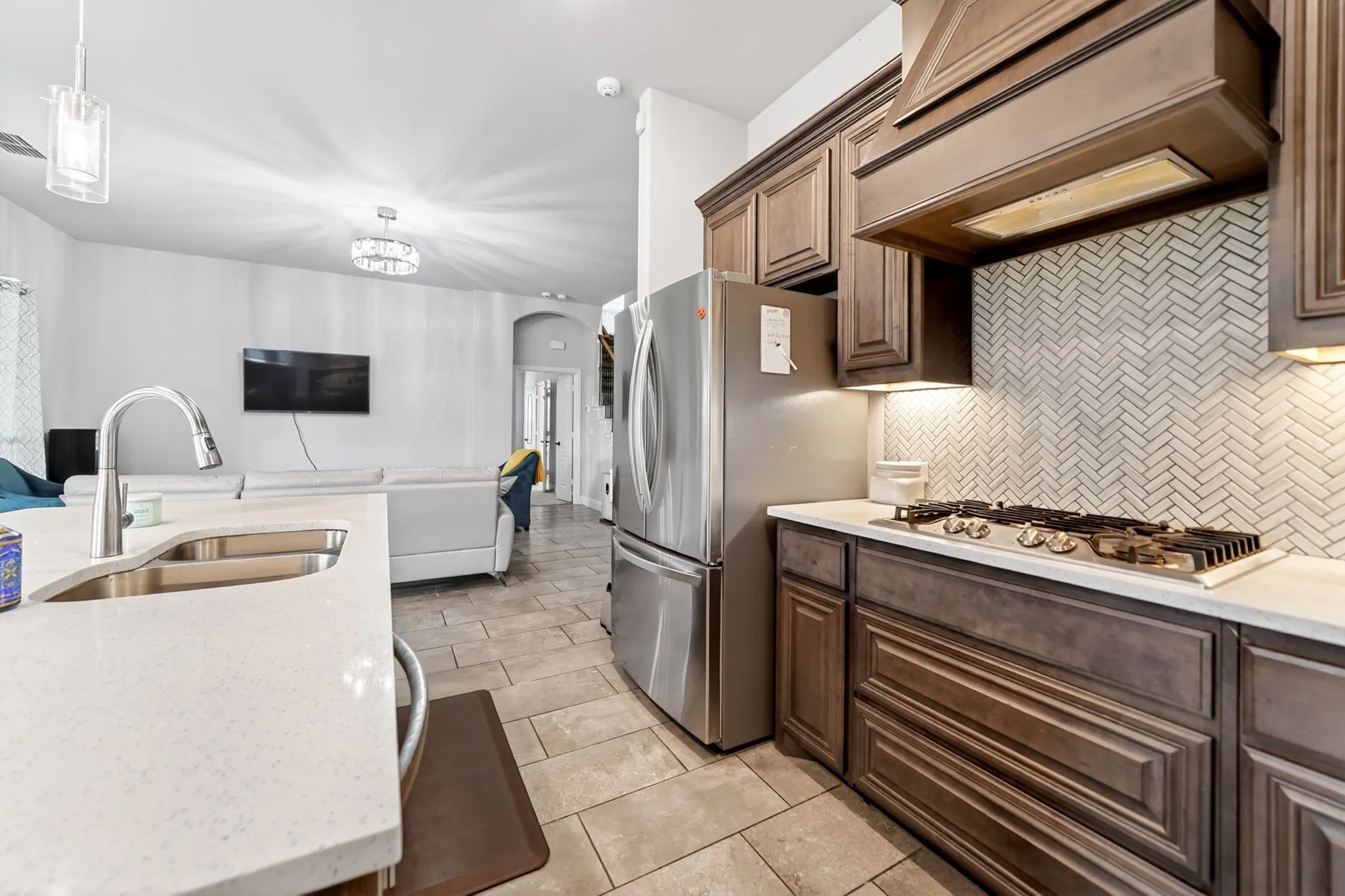 Kitchen featuring stainless steel appliances, herringbone tile backsplash, wood cabinetry, and a gas cooktop