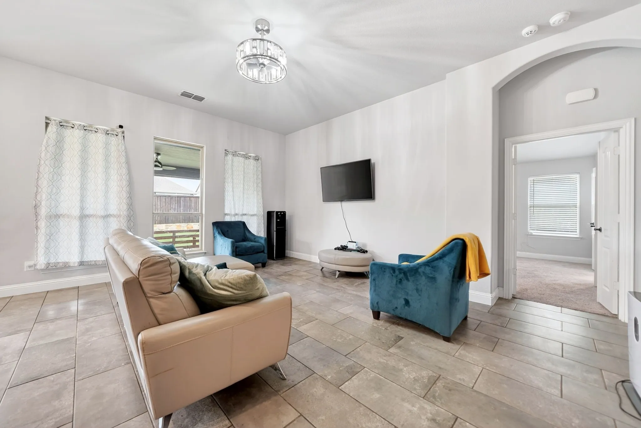Expansive room featuring tile flooring, a vaulted ceiling, and an arched entryway