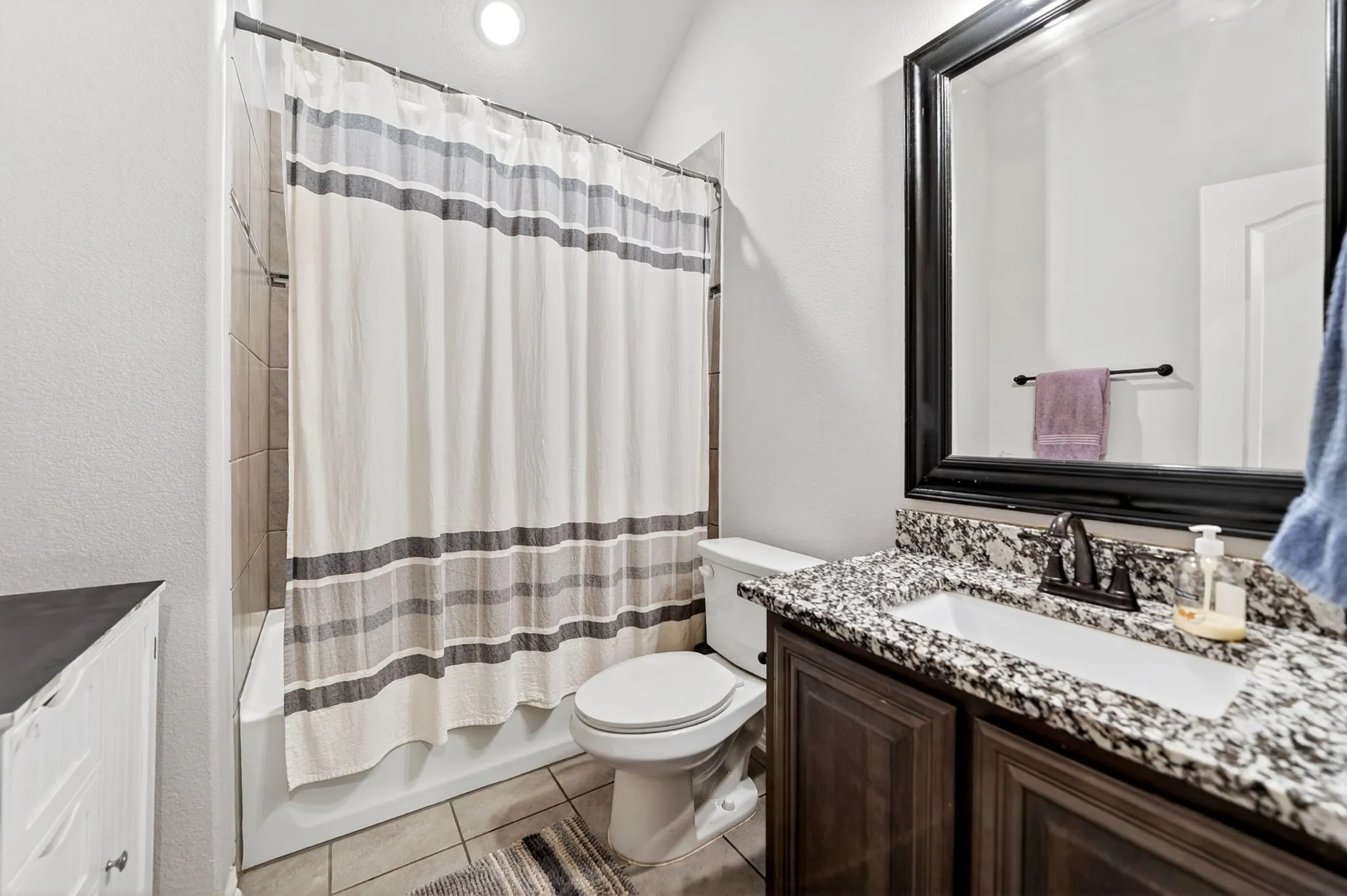 Vanity with a granite countertop and dark wood-finish cabinetry