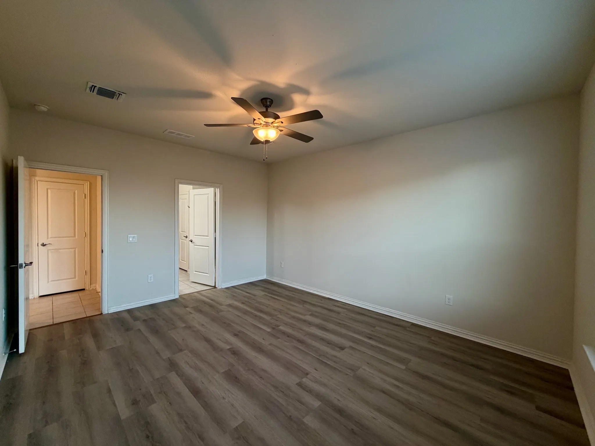 Wood-finish flooring, neutral wall tones, and a ceiling fan with integrated lighting