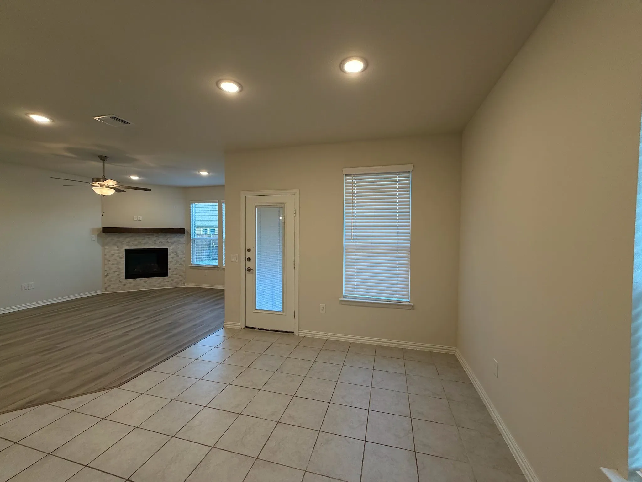 Tiled flooring complemented by recessed lighting and a window with blinds