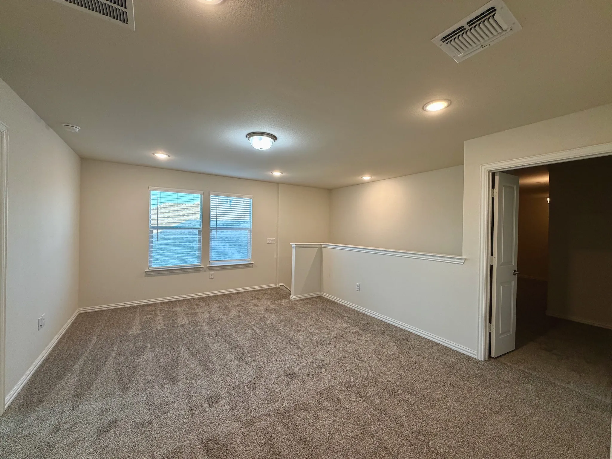 Carpeted room featuring recessed lighting, a ceiling-mounted light fixture, two windows with blinds, and painted walls