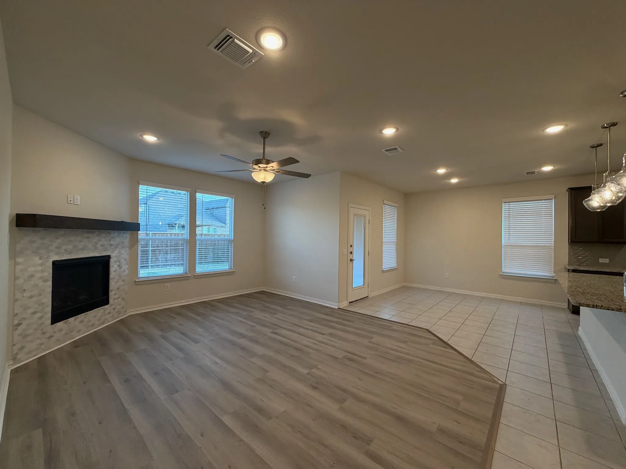 Corner fireplace with a wood mantel and tile surround, recessed lighting, wood-finish flooring, and a ceiling fan
