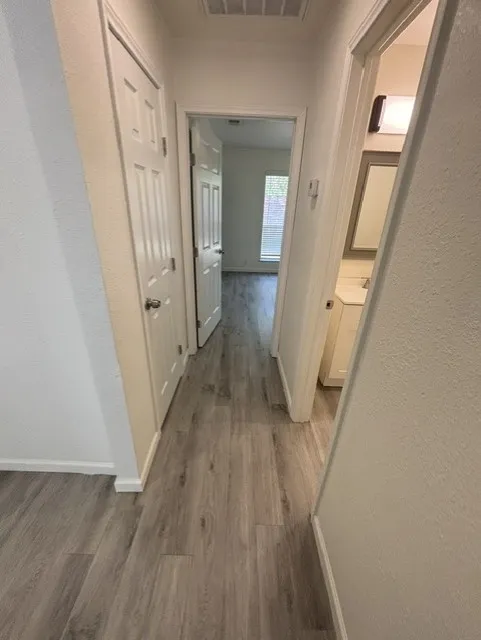 Hallway featuring wood-finish flooring, white paneled doors, and a neutral color palette