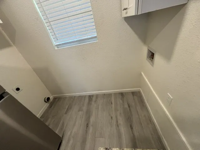 Wood-finish flooring, overhead window with blinds, and a built-in wall cabinet