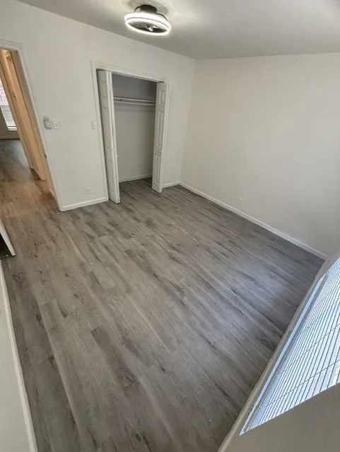 Wood-finish flooring with a closet featuring bi-fold doors and overhead shelving