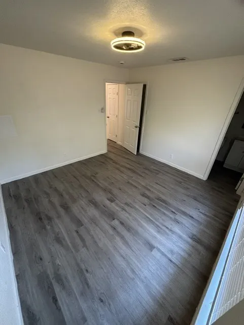 Wood-finish flooring, white walls, and a contemporary ceiling light fixture