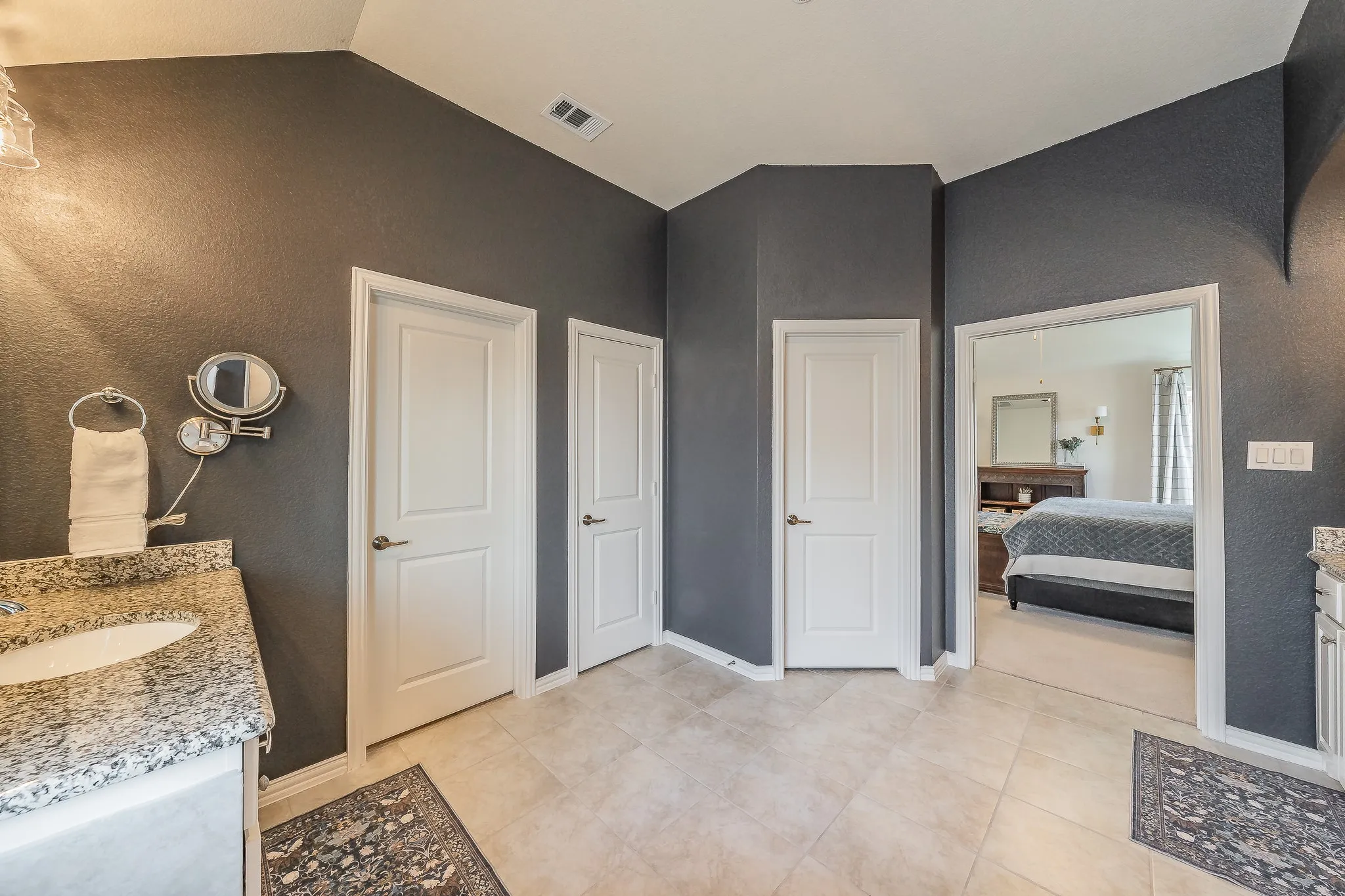 Bathroom featuring a built-in vanity with a granite-style countertop, undermount sink, and tiled flooring