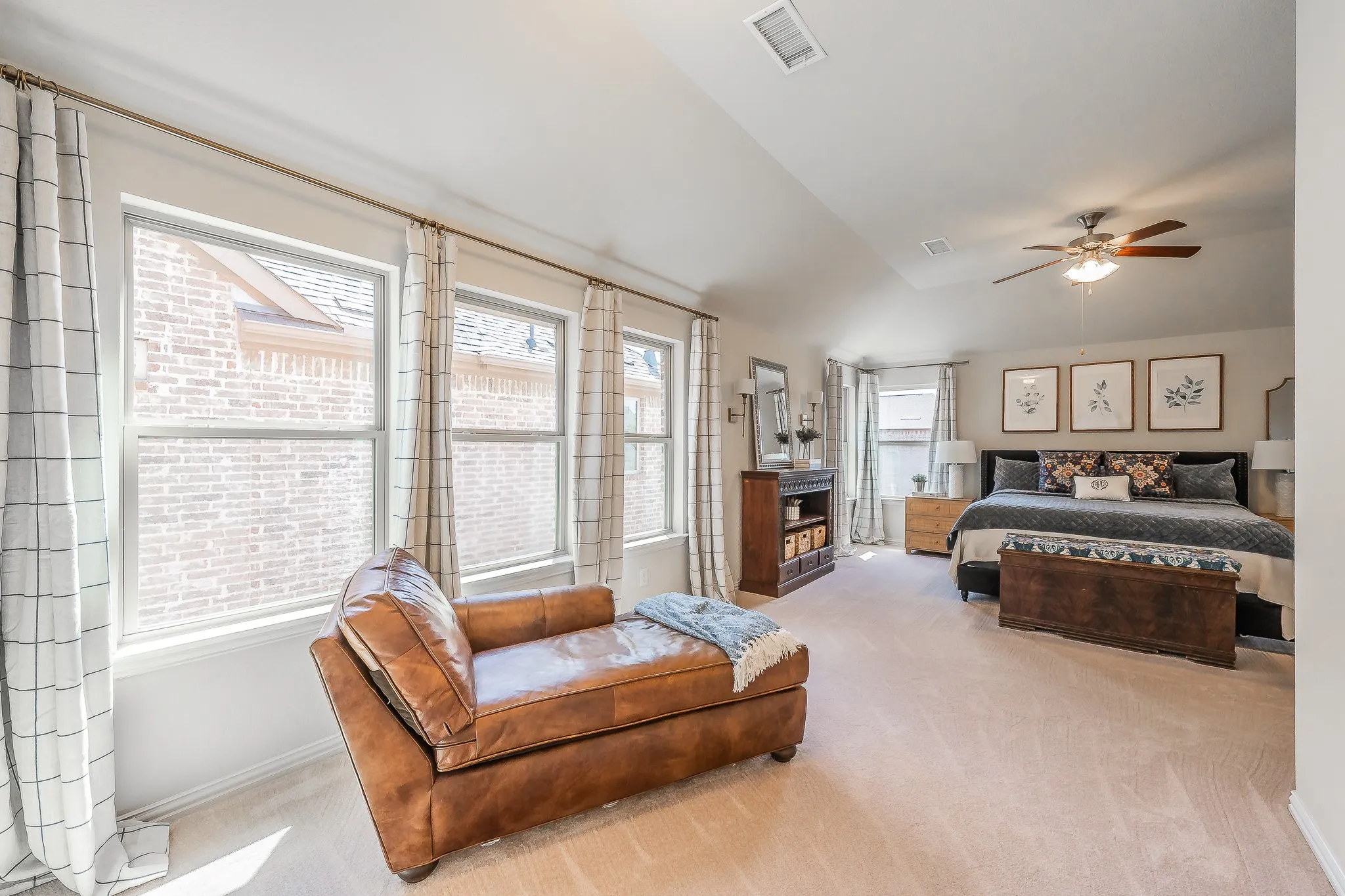 Vaulted ceiling, ceiling fan, and multiple windows with crown molding