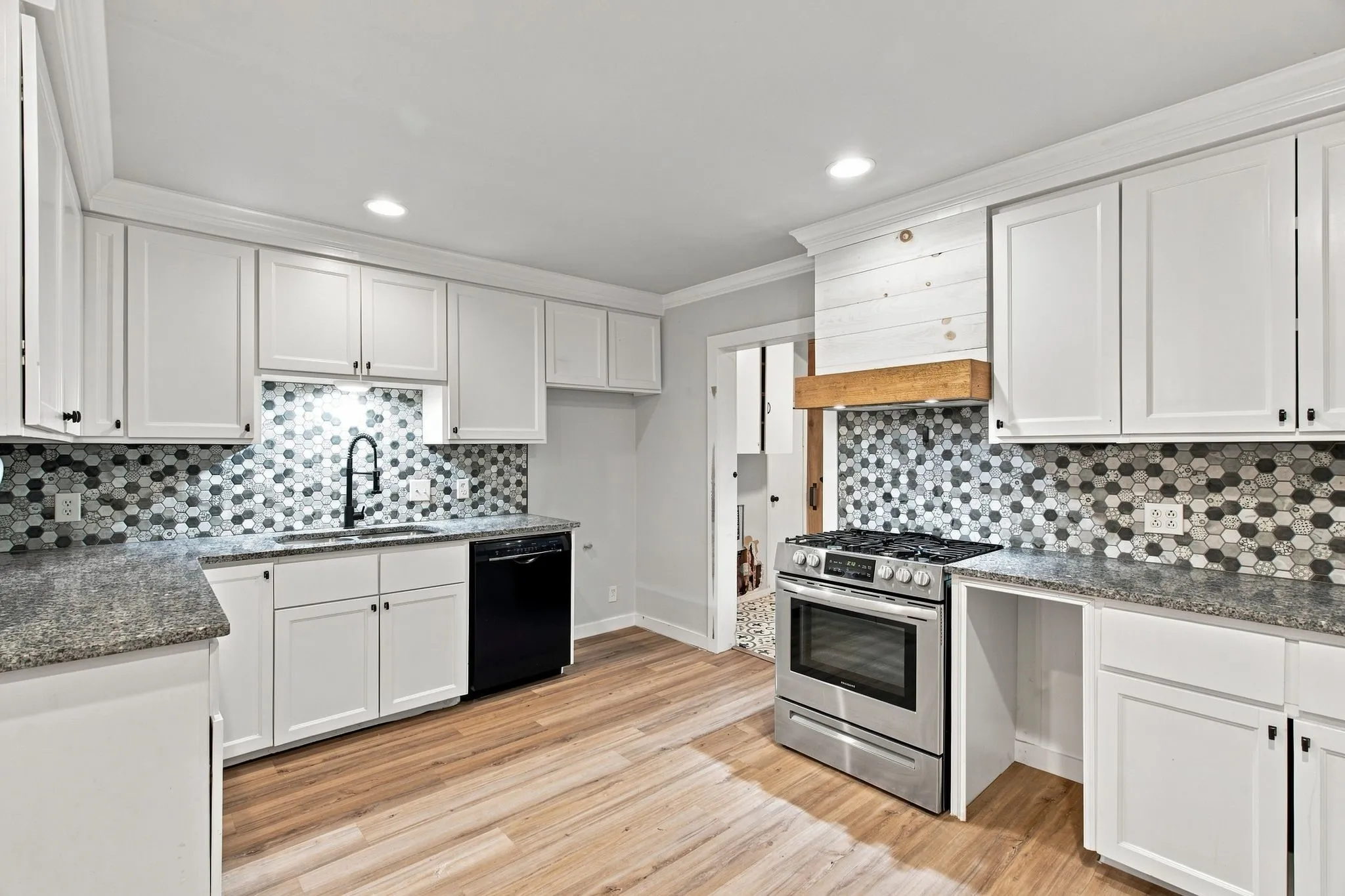 White shaker cabinetry, honeycomb tile backsplash, stainless steel appliances, wood-finish flooring, and recessed lighting