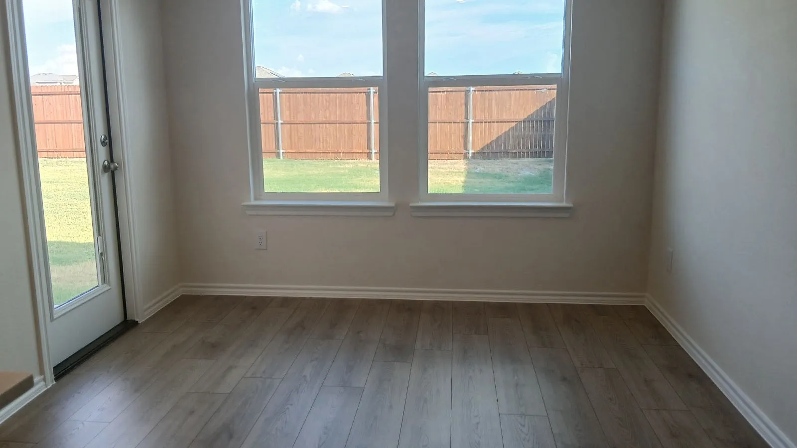 Wood-finish flooring, white trim, dual pane windows, and a glass-paneled exterior door