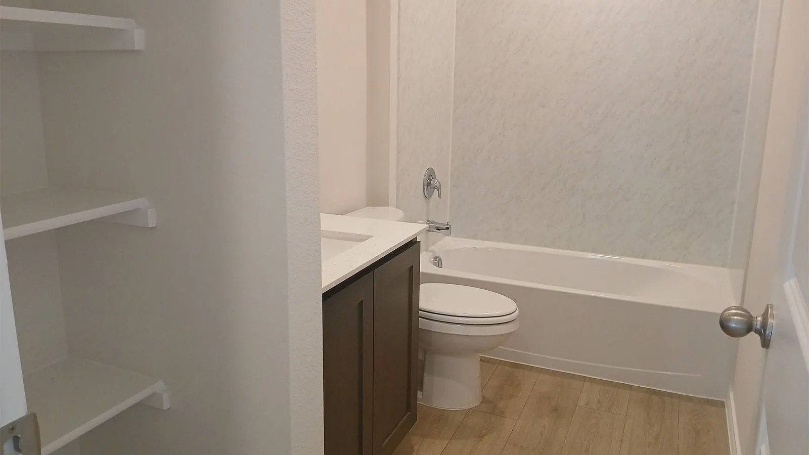 Bathroom featuring a built-in tub with shower, wood-finish flooring, and a vanity with an integrated sink