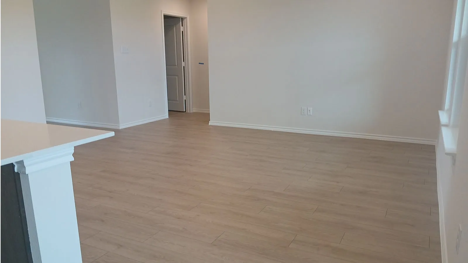 Spacious interior featuring wood-finish flooring, white walls, and a visible doorway