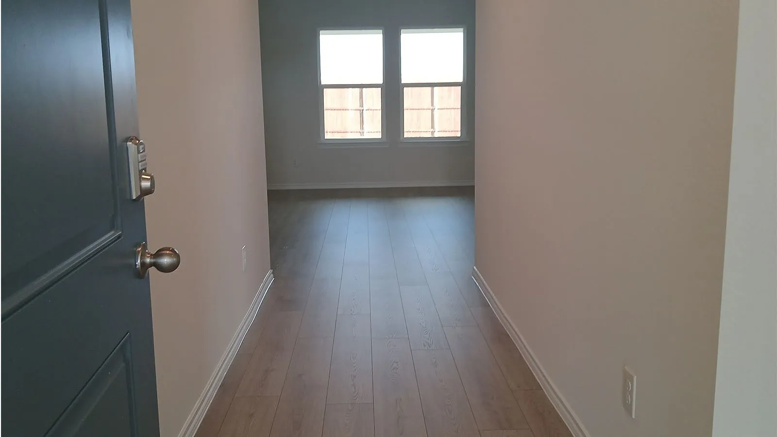 Entryway featuring a dark paneled door with keyless entry, wood-finish flooring, and light-toned​​‌​​​​‌​​‌‌​‌‌​​​‌‌​‌​‌​‌​​​‌​​ walls