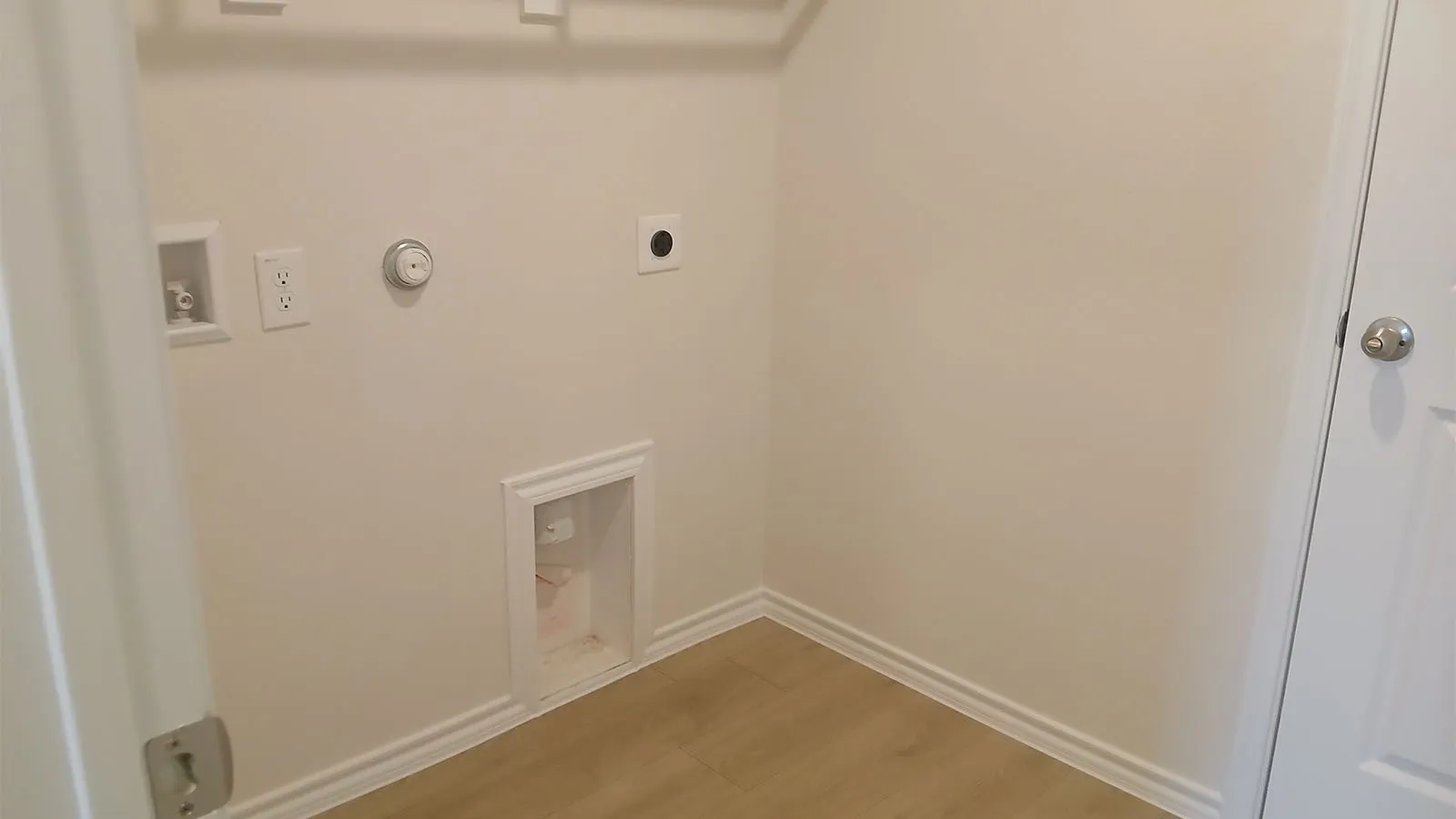 Dedicated laundry area featuring a wood-finish floor and white trim