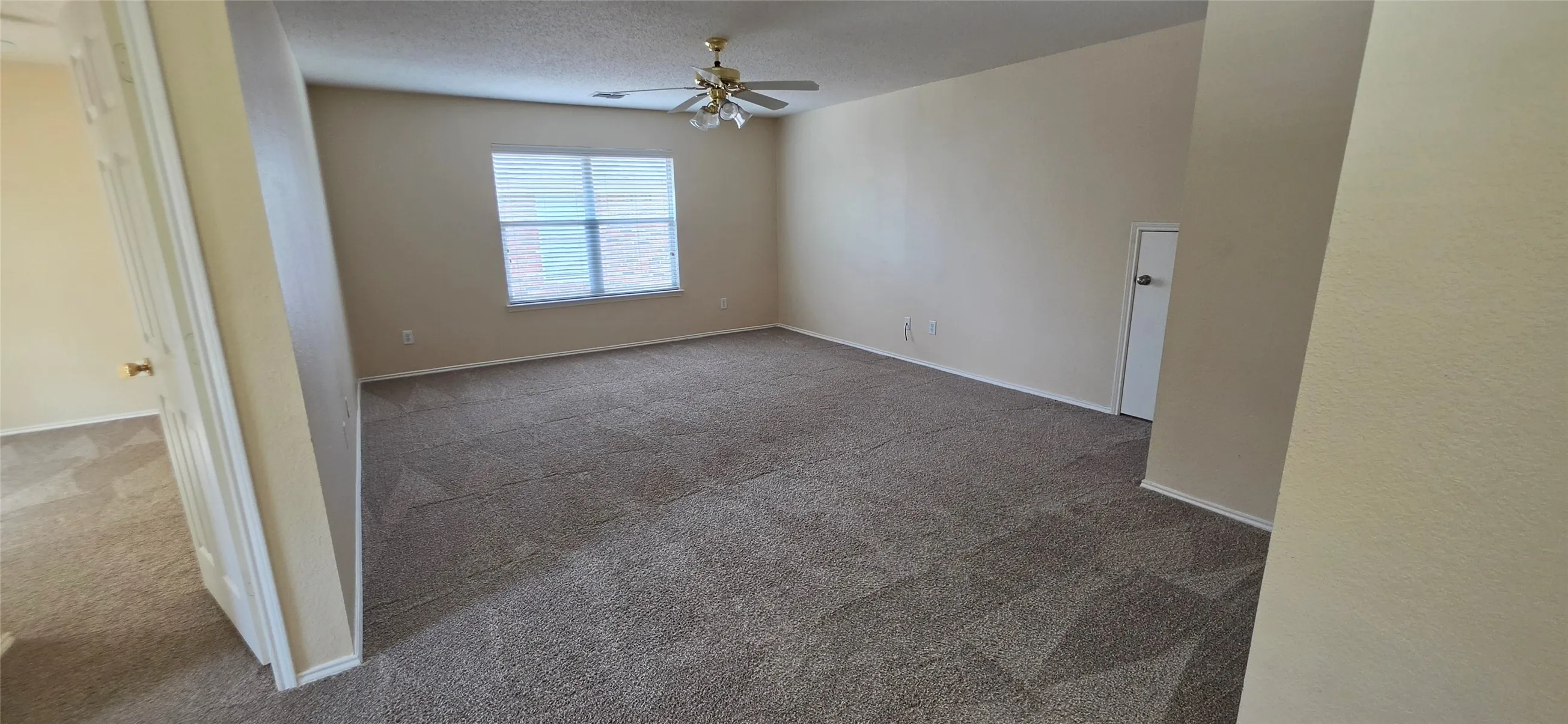 Spacious room featuring carpeting, a window with horizontal blinds, a ceiling fan, and light-toned walls