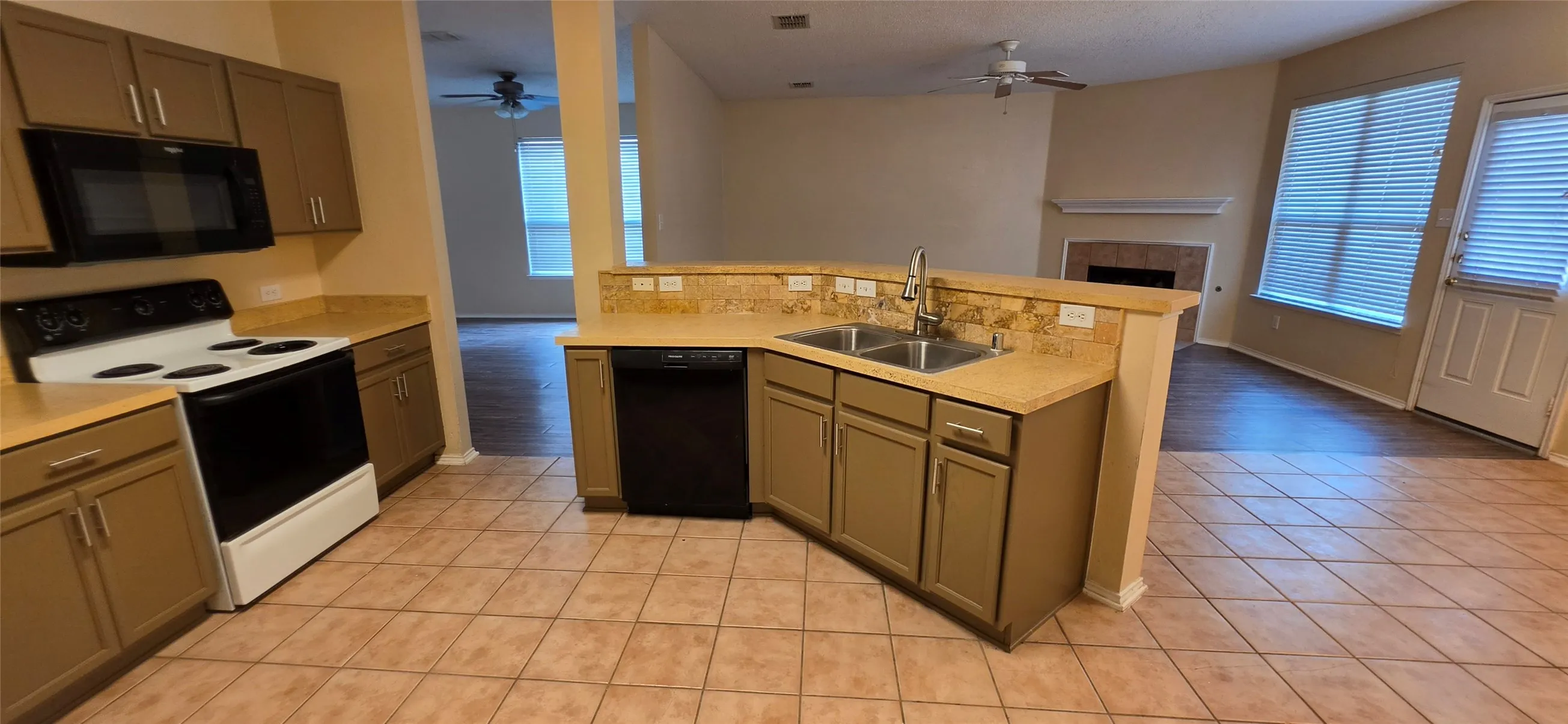 Kitchen featuring tile flooring, a dual basin sink, integrated dishwasher, and built-in microwave