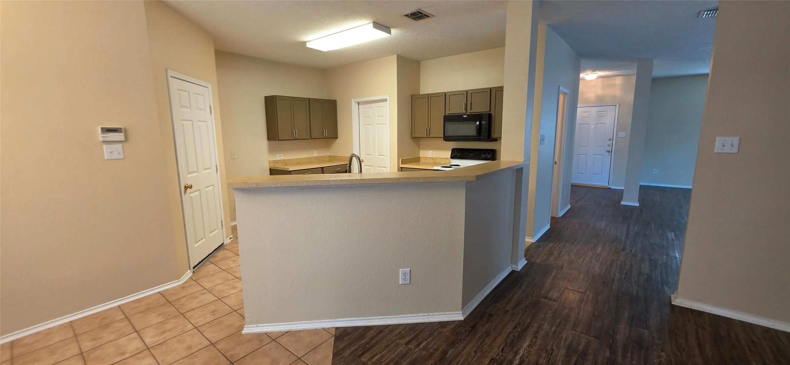 Kitchen featuring a breakfast bar, dark-finish cabinetry, built-in microwave, and stainless steel sink