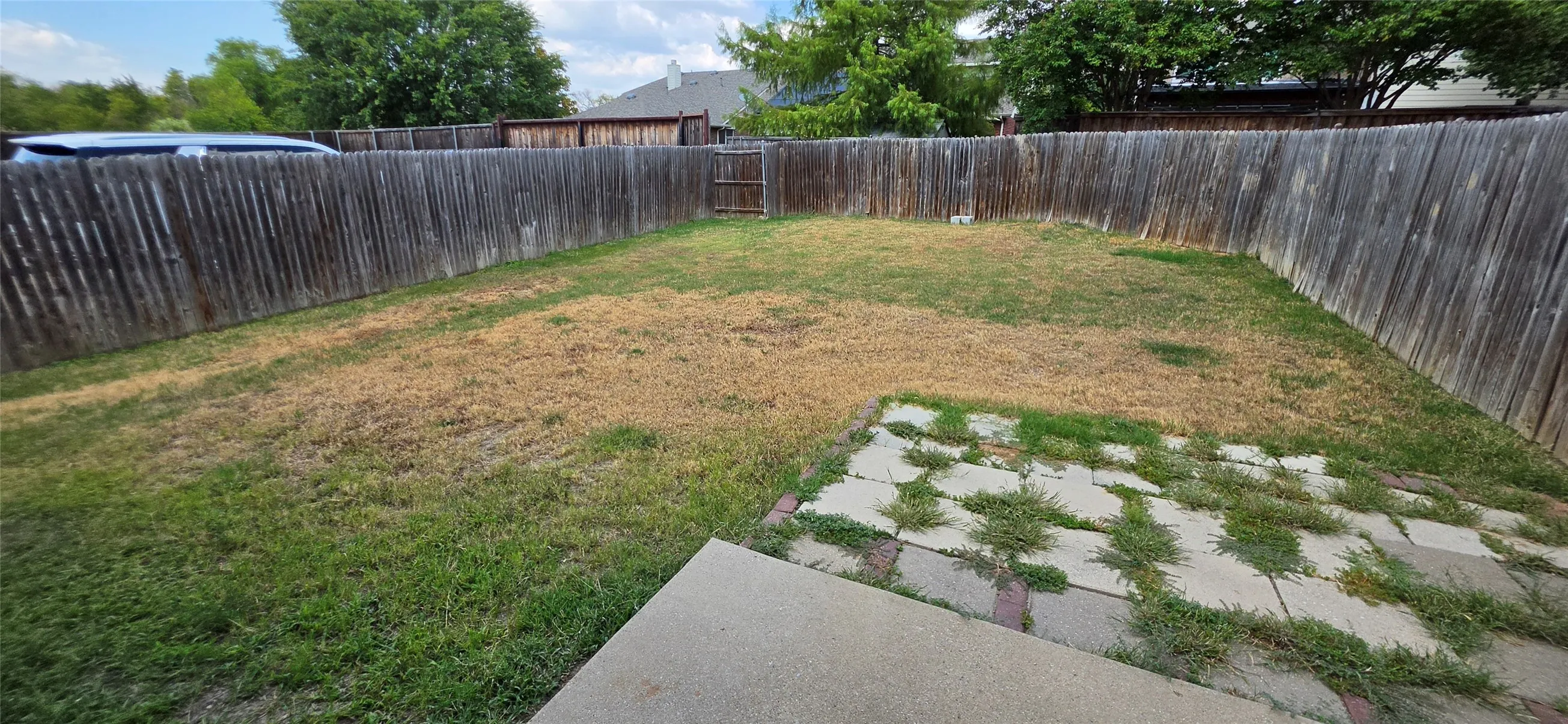Fenced backyard featuring a concrete patio and stepping stones