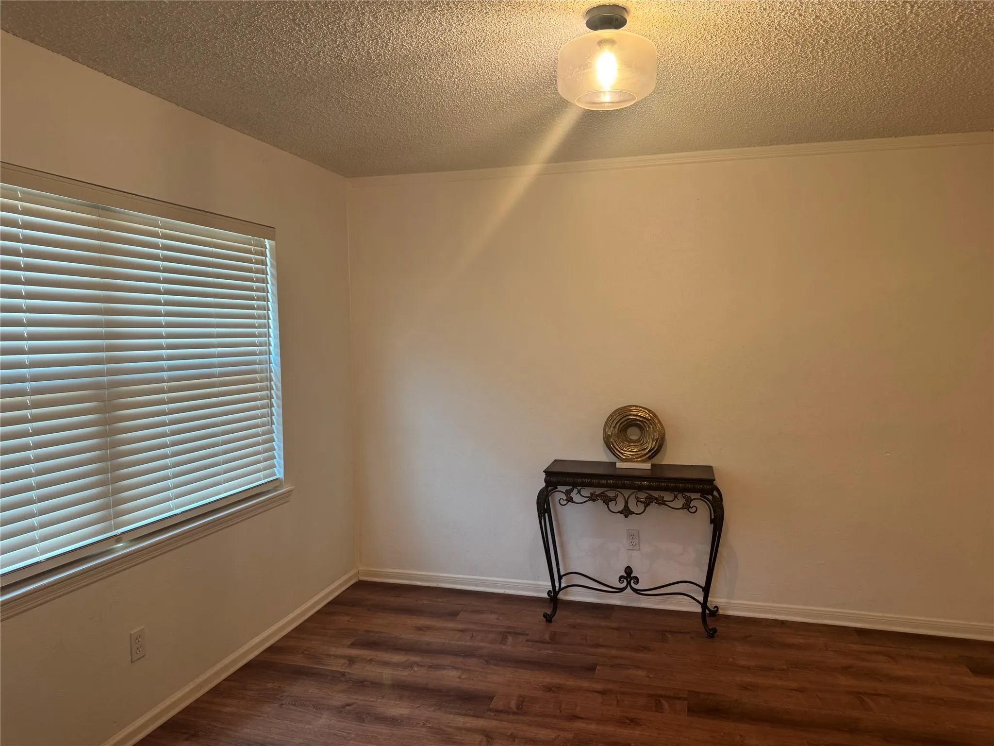 Wood-finish flooring, white walls, and a window with blinds