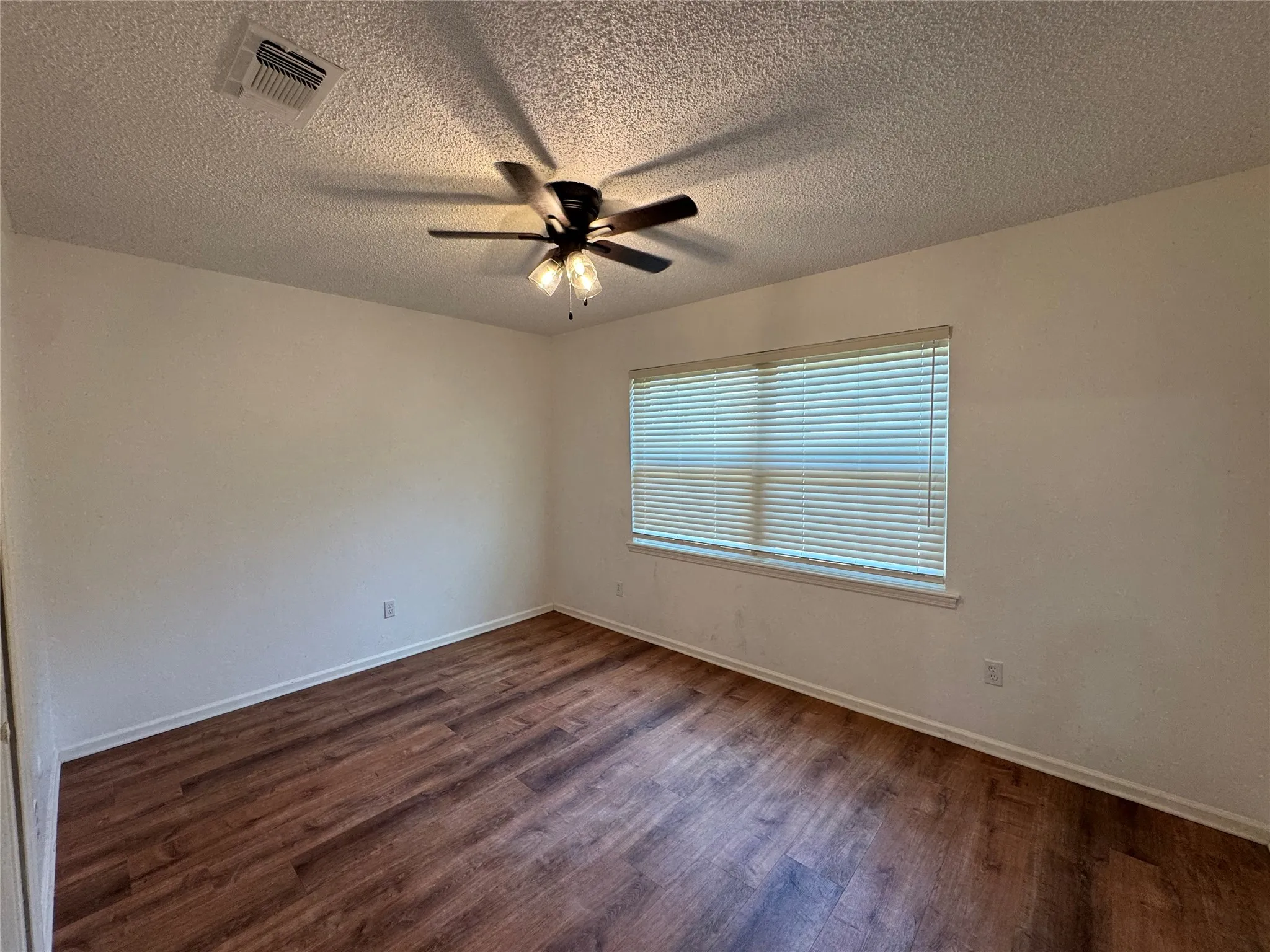 Bedroom with blinds, wood-finish flooring, ceiling fan with integrated lighting, and neutral wall paint