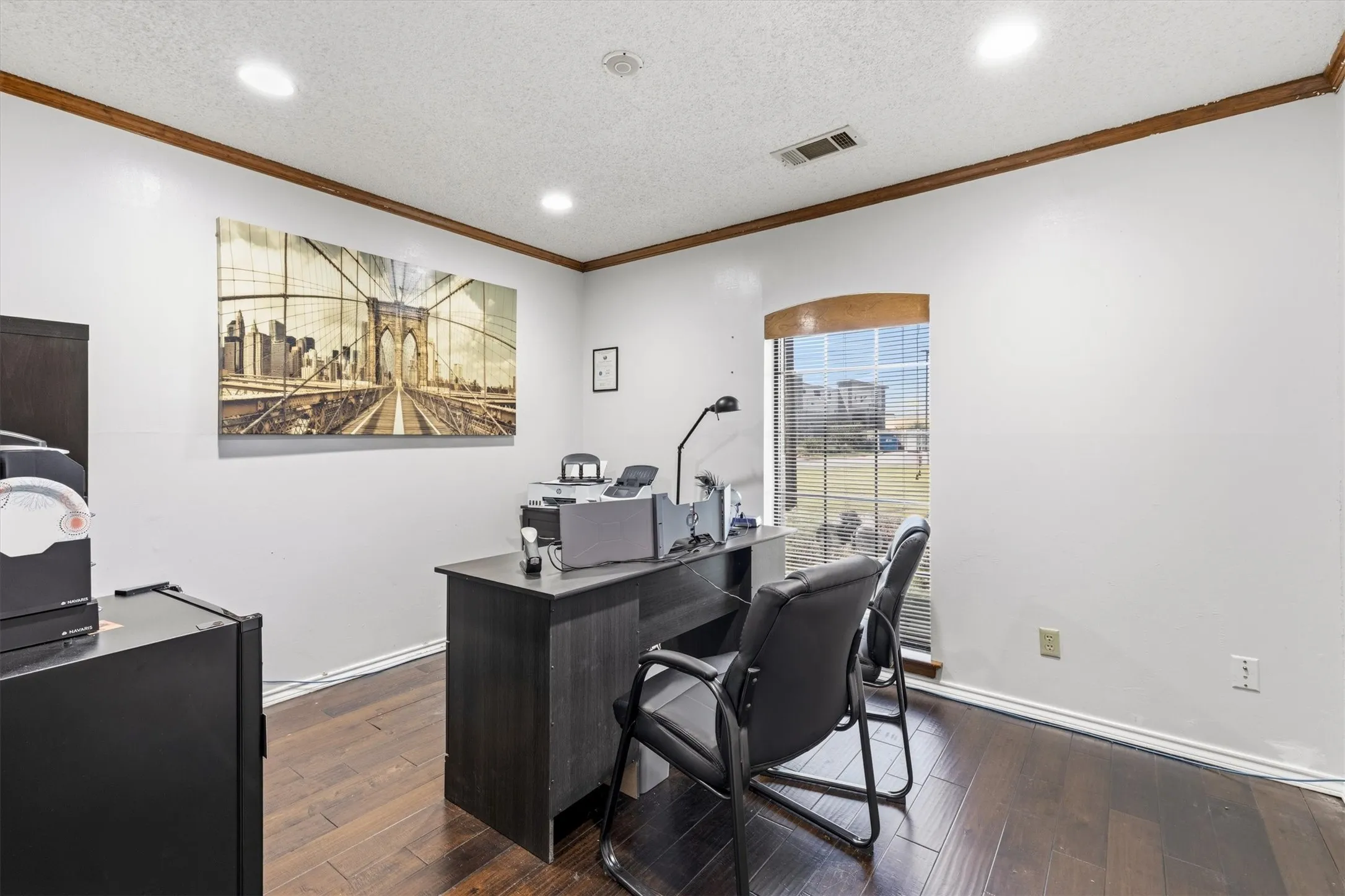 Hardwood flooring, recessed ceiling lighting, a curved window, and crown molding