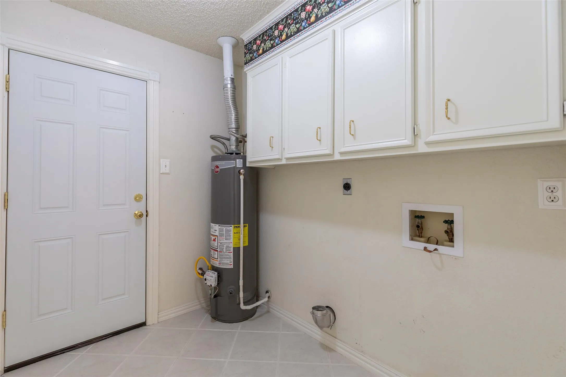 White paneled door with gold-tone hardware, gray tile flooring, and white upper cabinetry