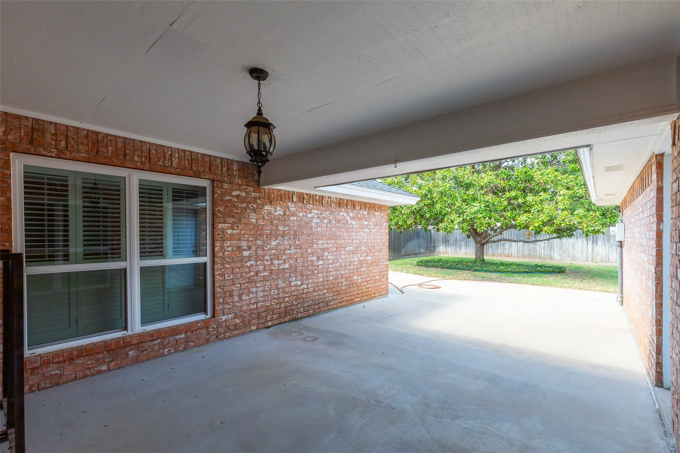 Covered patio with a concrete surface, brick exterior, and an exterior hanging light fixture