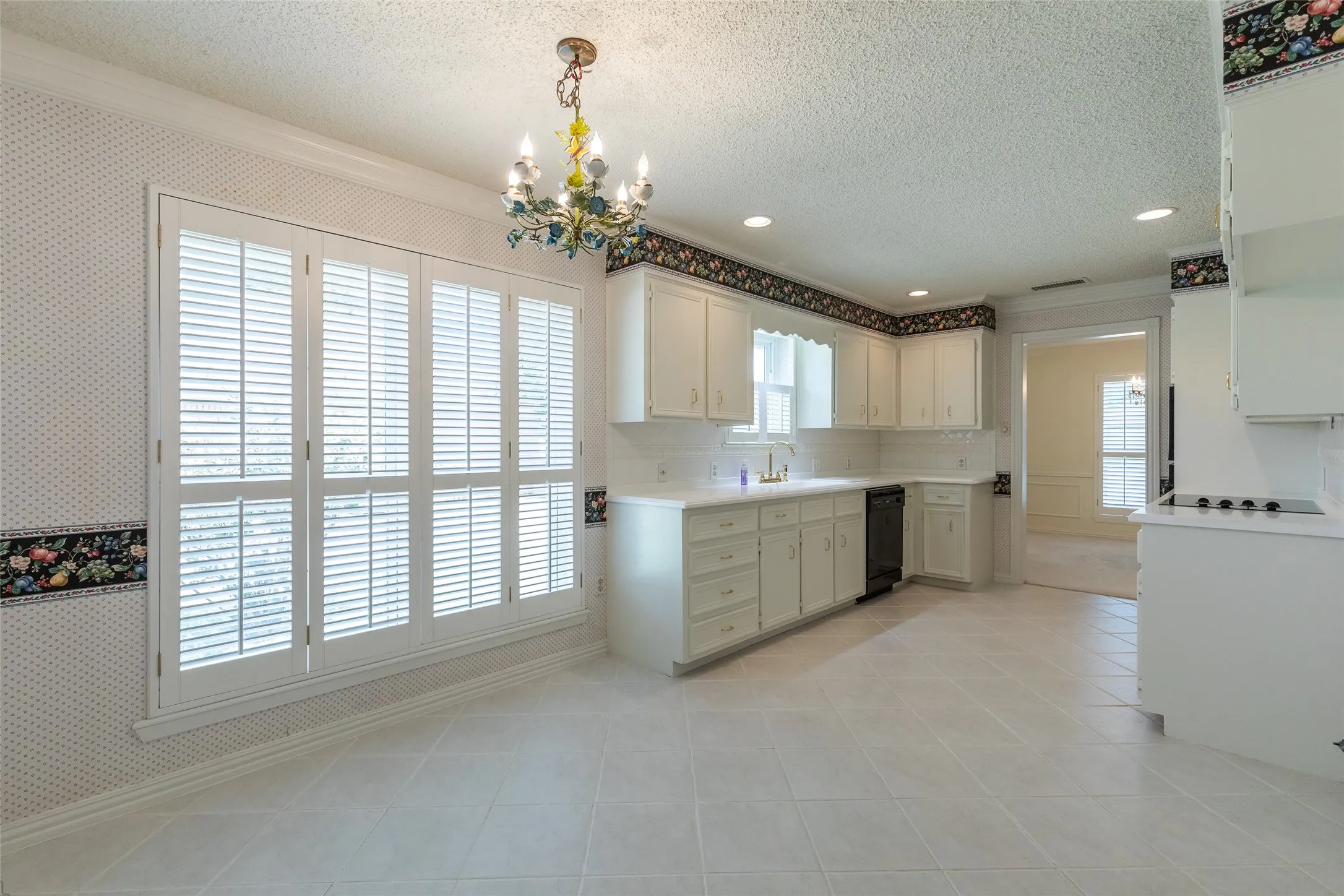 White cabinetry with integrated appliances, extensive counter space, and a tile backsplash