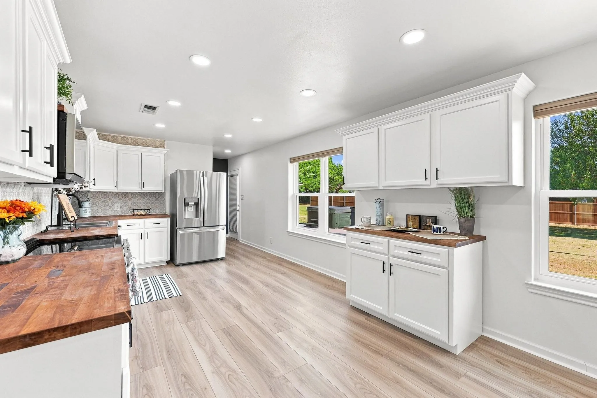 Bright kitchen featuring white cabinetry, wood-finish countertops, stainless steel appliances, and wood-finish flooring