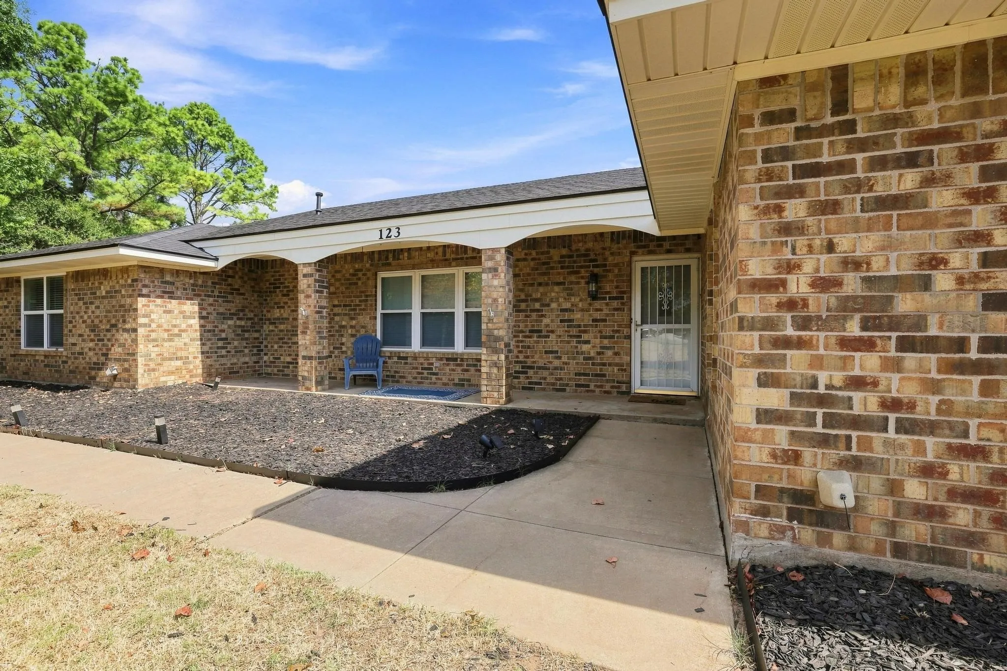 Brick exterior with white trim, covered front entry, and a paved walkway